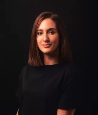 young brown-haired woman smiles sweetly in the rays of light in a dark room