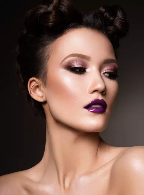 girl with a high hairstyle and purple lips looks to the side