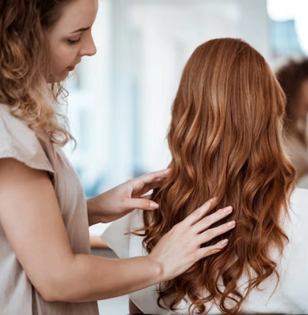 A brown-haired girl has her hair straightened from behind