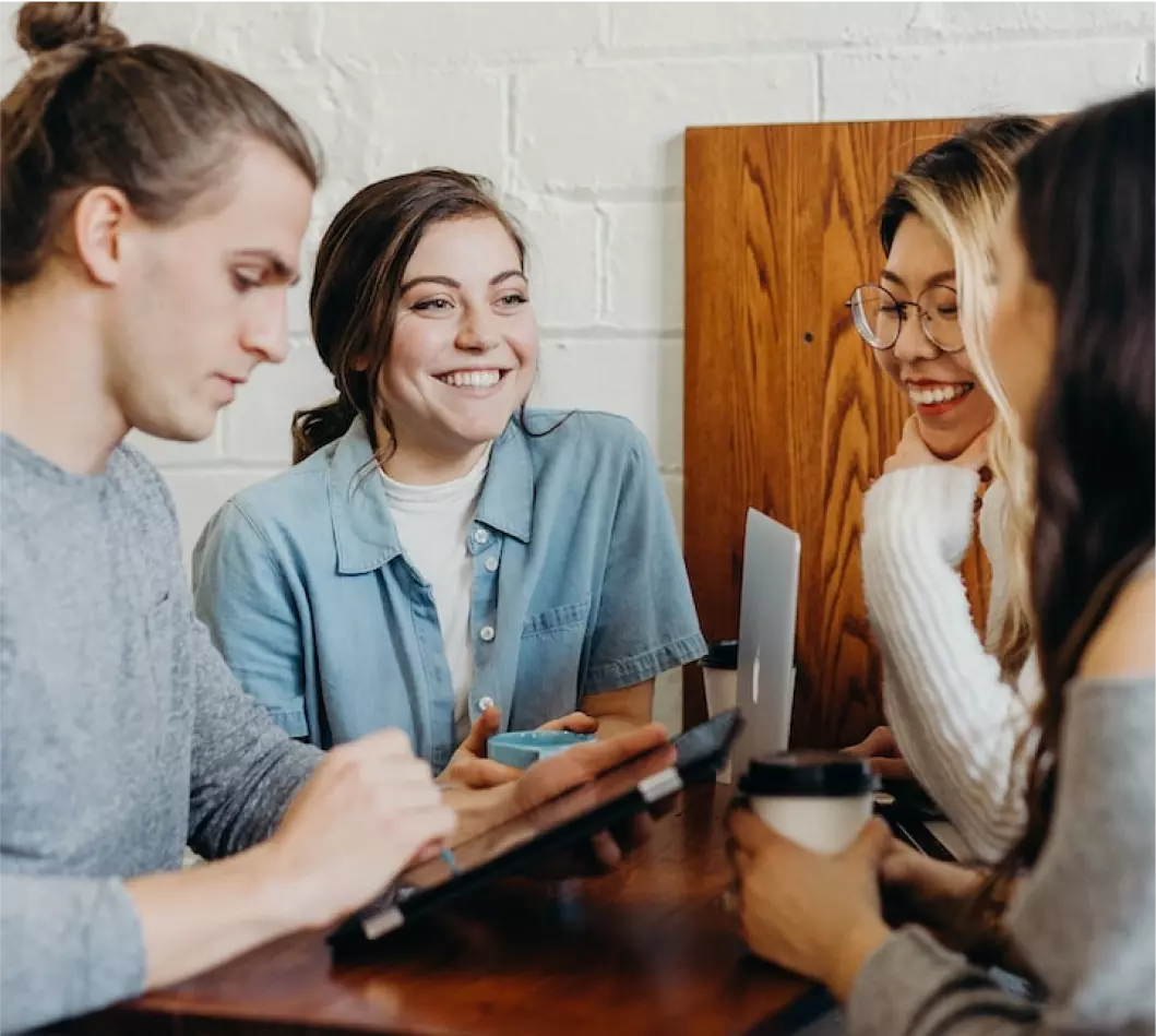 a group of friends sitting at the table and laughing