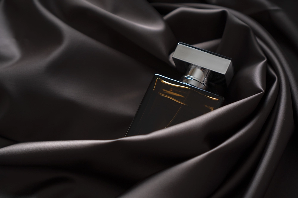 a dark bottle of perfume wrapped in brown cloth