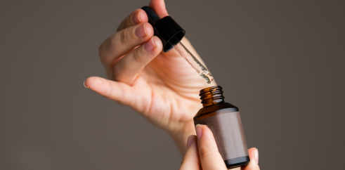 female hands holding a bottle with a pipette