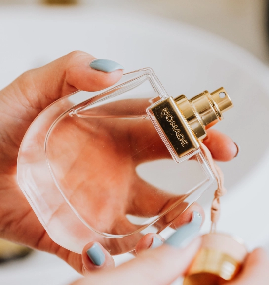 female hand with painted nails holds a bottle of perfume