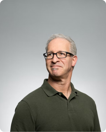 gray-haired man with glasses looks into the distance