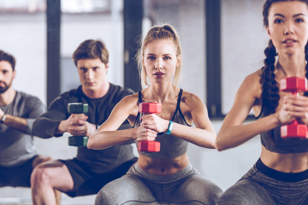 a girl and a guy perform a static exercise, squats with dumbbells