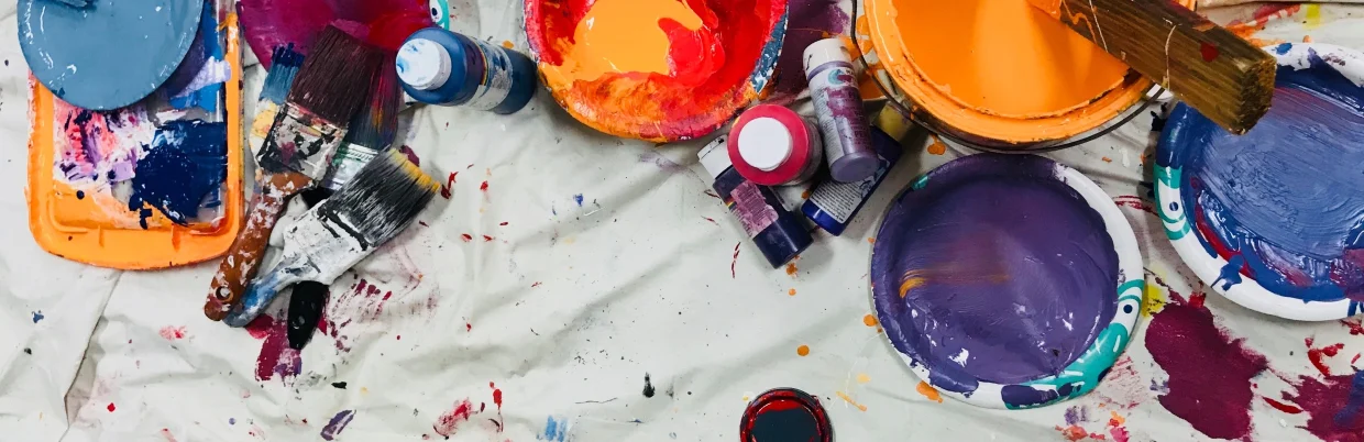 cans of paints with used brushes lie on a white cloth