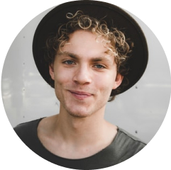 a young guy with curly blond hair sticking out from under a black hat