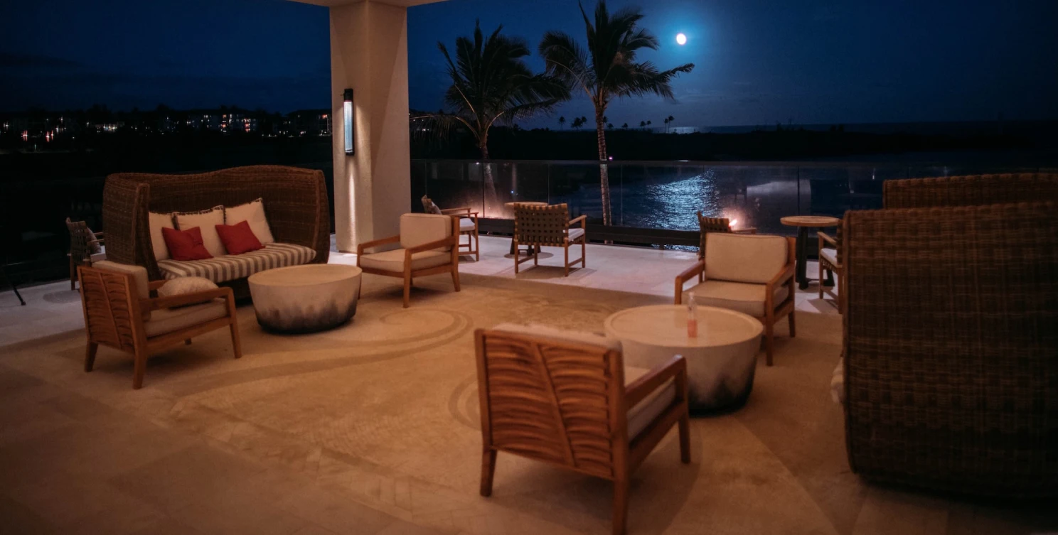 large terrace with coffee tables and armchairs, which overlooks the night ocean