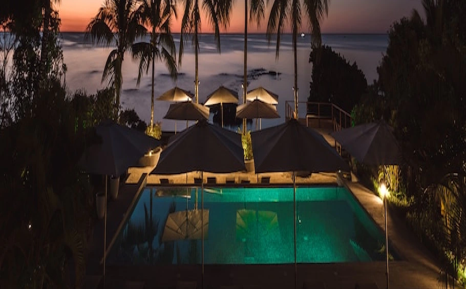 view from the balcony to the ocean, pool and palm trees