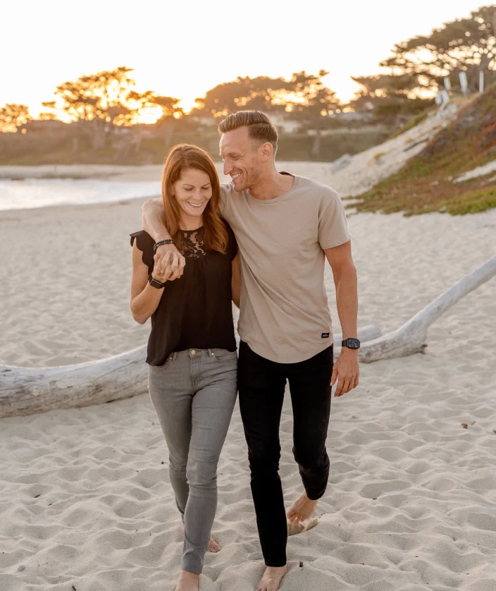 a guy and a girl walking on the sand