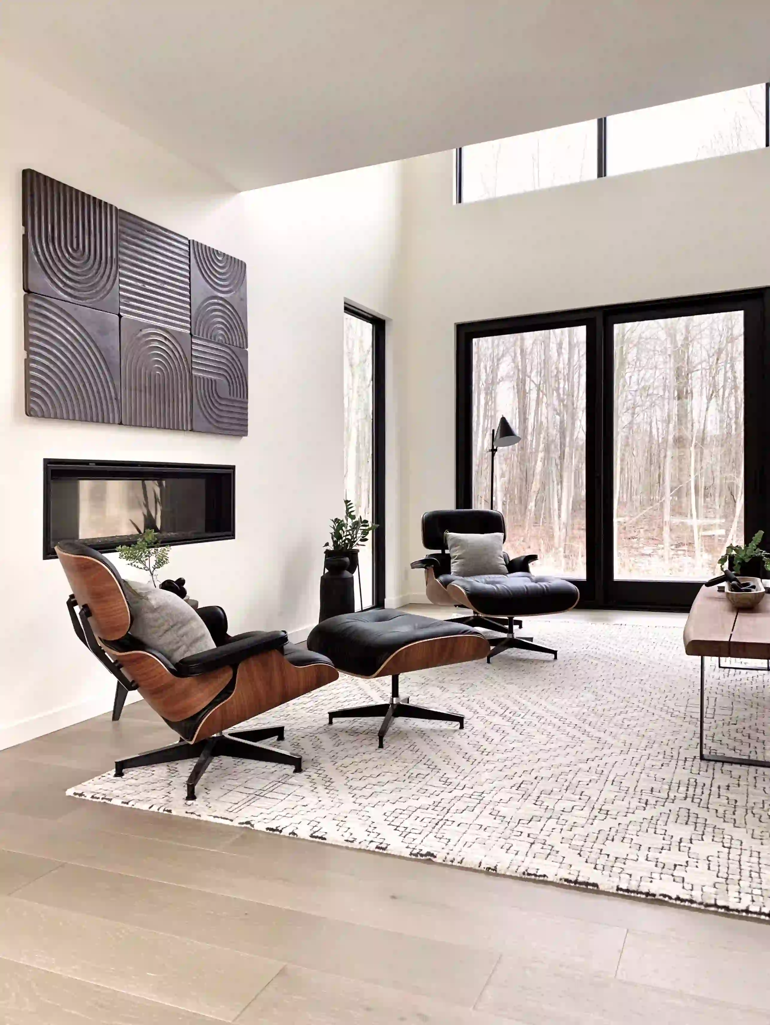 bright room with large windows and dark armchairs with footrests