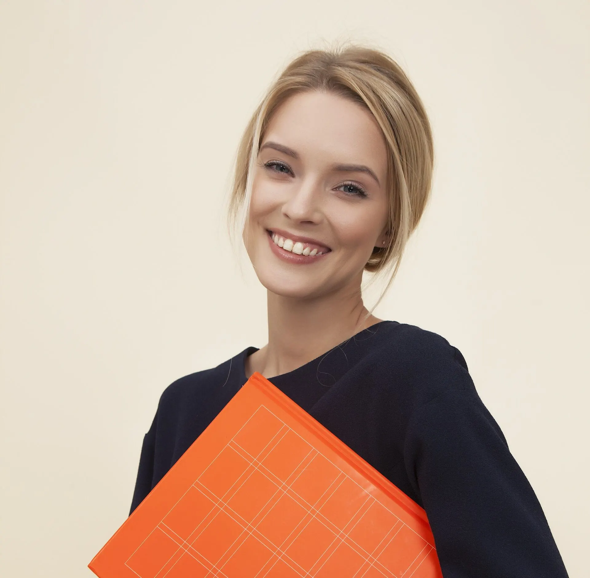 Blonde girl in dark clothes holding an orange folder in her hands