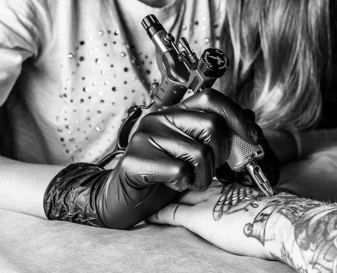 ein Tätowierer füllt ein Tattoo auf dem Arm