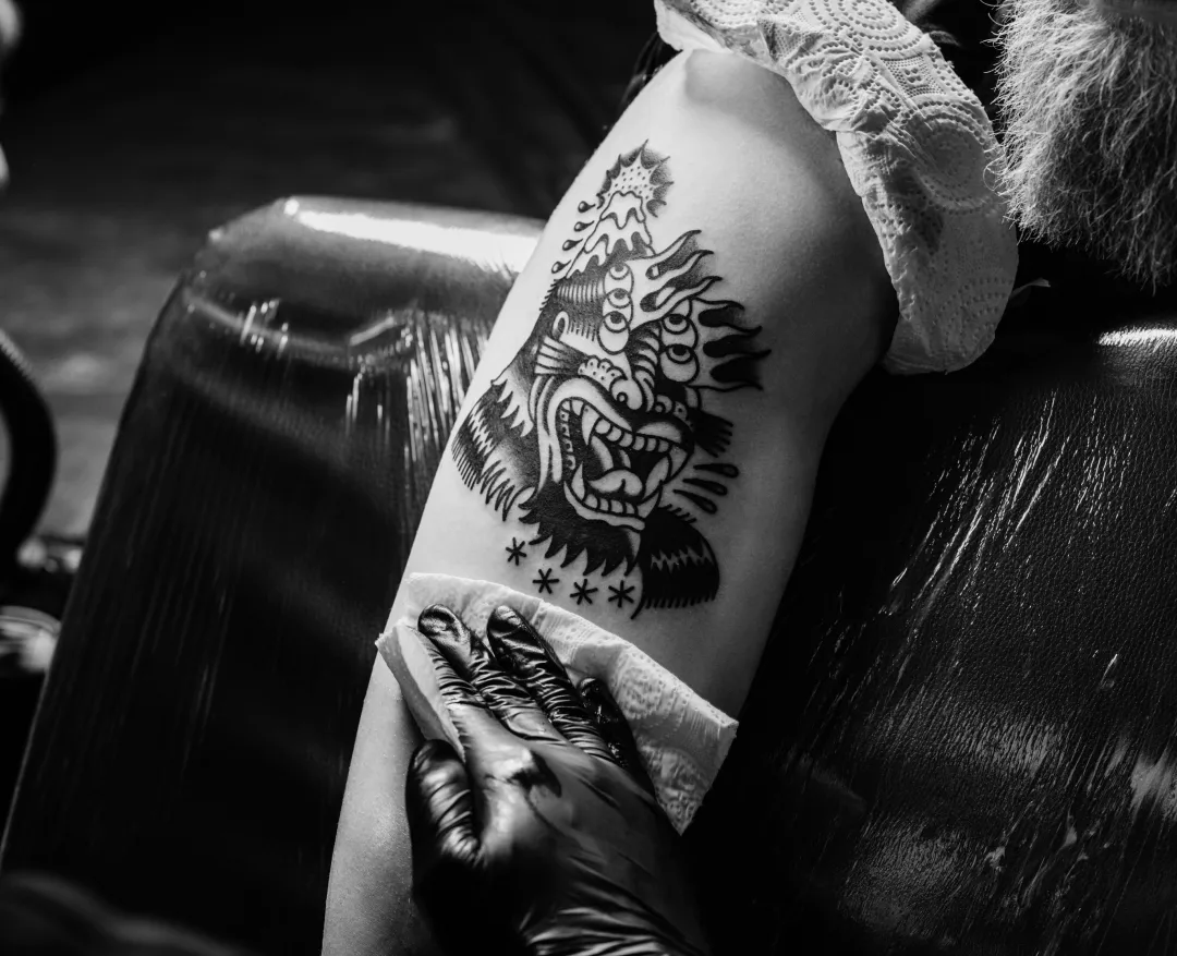 un tatuatore fa un tatuaggio sul braccio