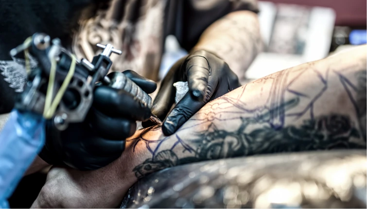 o tatuador faz uma tatuagem no braço