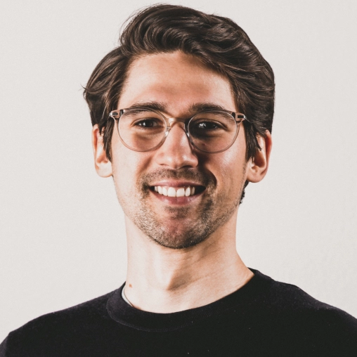 brown-haired guy with glasses smiles widely