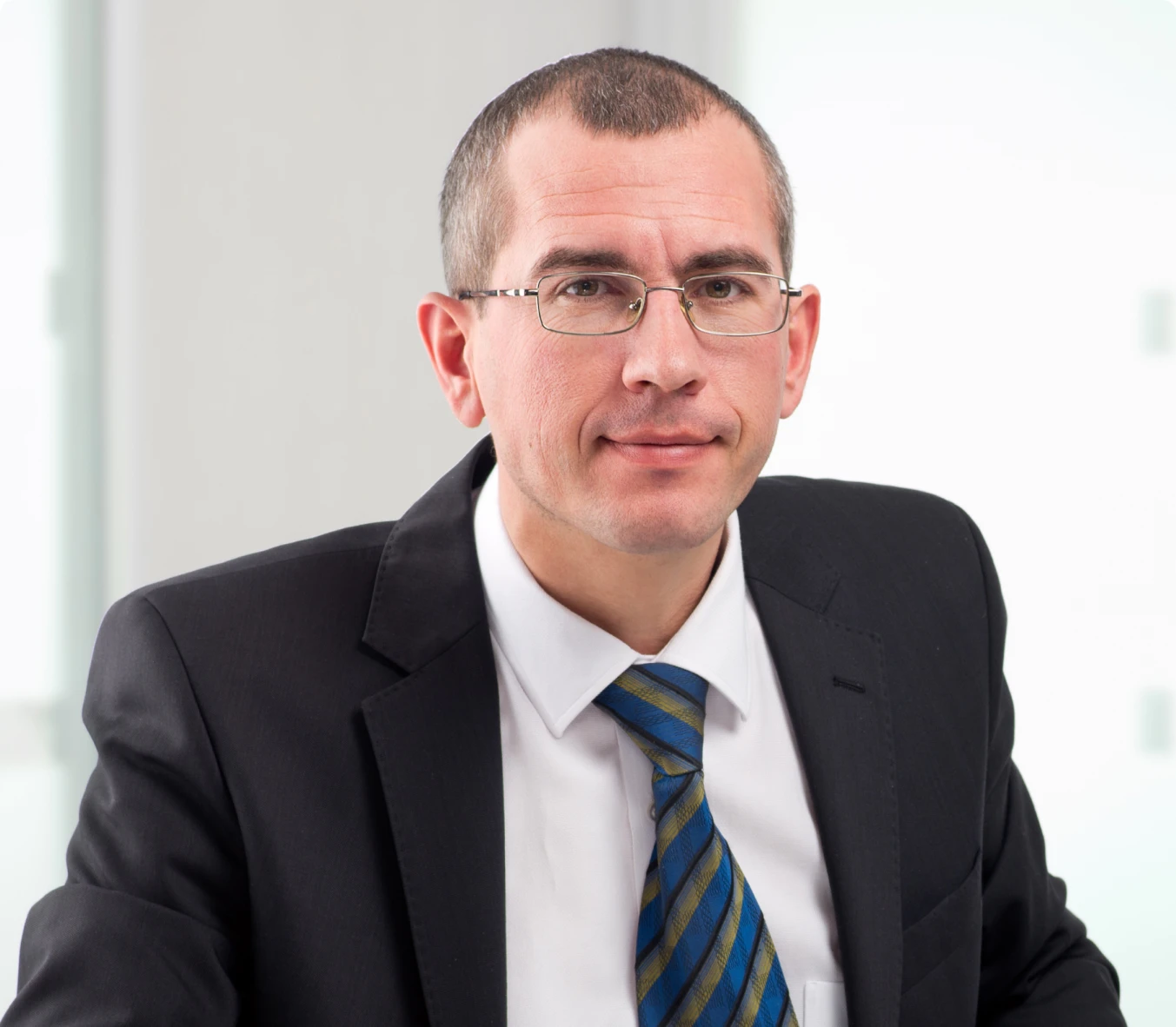 a man with a short haircut, glasses and a strict black suit