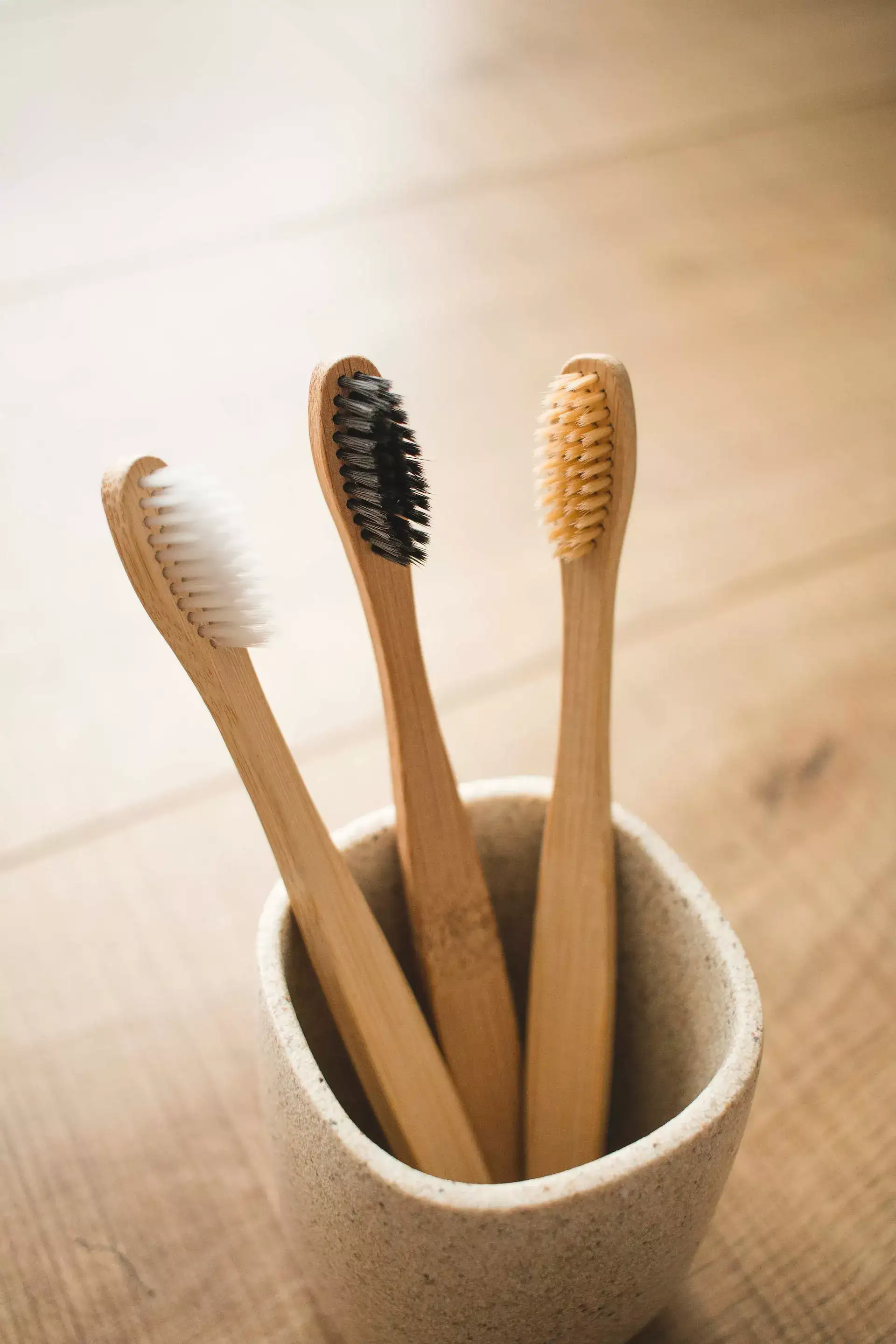 three toothbrushes in a white glass