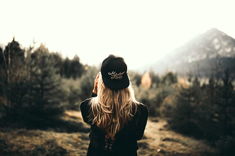 uma garota com roupas pretas perto das montanhas