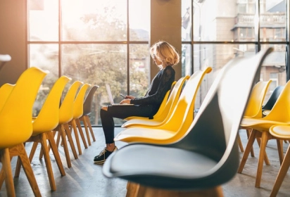 sala de vidro vazia com cadeiras amarelas e uma pessoa sentada